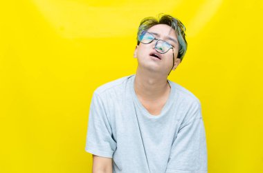 Sarı arka planda stresli Asyalı genç adam 