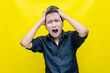 Asyalı genç adam sarı arka planda stresli 