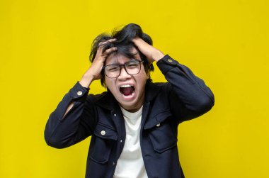 Sarı arka planda bağıran Asyalı genç adam. 
