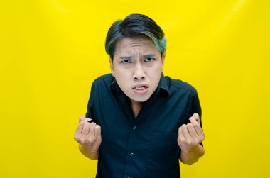 Asyalı öfkeli genç adam sarı arka planda. 