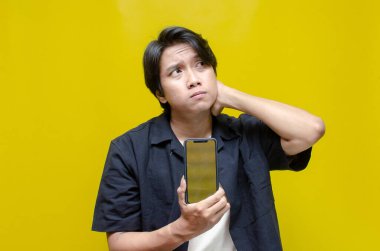 Sarı arka planda akıllı telefonu olan genç Asyalı adam. 