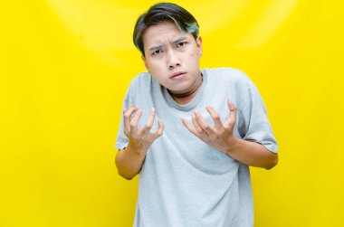 Asyalı öfkeli genç adam sarı arka planda 