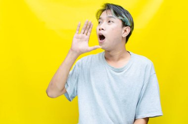 Sarı arka planda bağıran Asyalı genç adamın portresi 