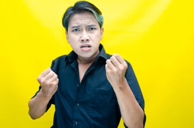 Sarı arka planda bağıran kızgın Asyalı adam 