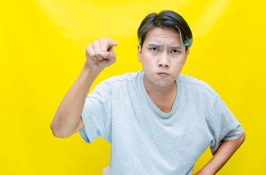 Asyalı kızgın genç bir adamın portresi sarı arka planda seni işaret ediyor..