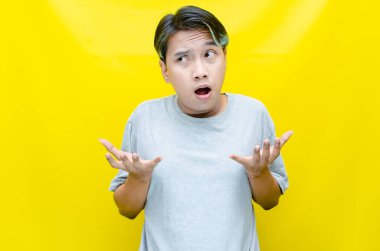 Hüsrana uğramış genç Asyalı adam sarı arka planda 