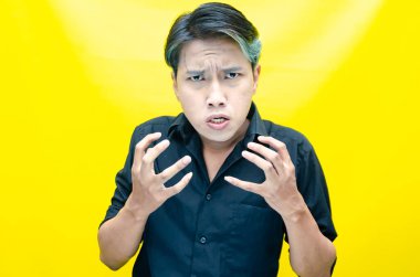 Asyalı öfkeli genç adam sarı arka planda. 