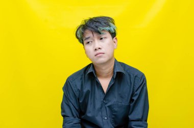 Hüsrana uğramış genç Asyalı adam sarı arka planda 