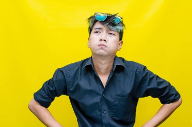 Hüsrana uğramış genç Asyalı adam sarı arka planda 