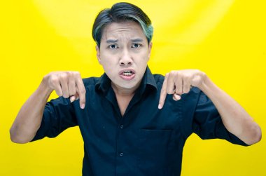 Asyalı öfkeli genç adam sarı arka planda. 