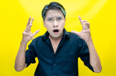 Sarı arka planda stresli Asyalı genç adam 