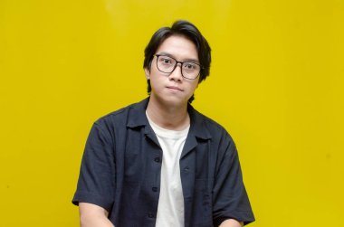 Beyaz arka planda siyah gömlekli Asyalı genç bir adamın portresi.