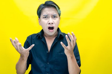 Sarı arka planda bağıran kızgın Asyalı adam 