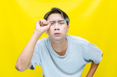 Sarı arka planda ağlayan genç Asyalı adam 