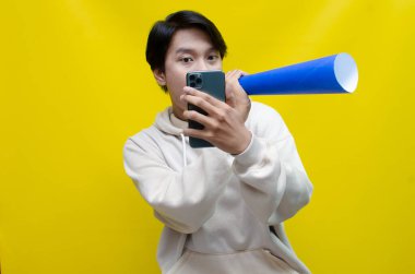 Neşeli ve kendini ifade eden Asyalı bir adam megafona bağırıyor.