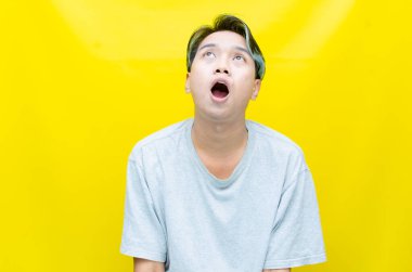 Sarı arka planda ağzı açık Asyalı genç bir adamın portresi. 
