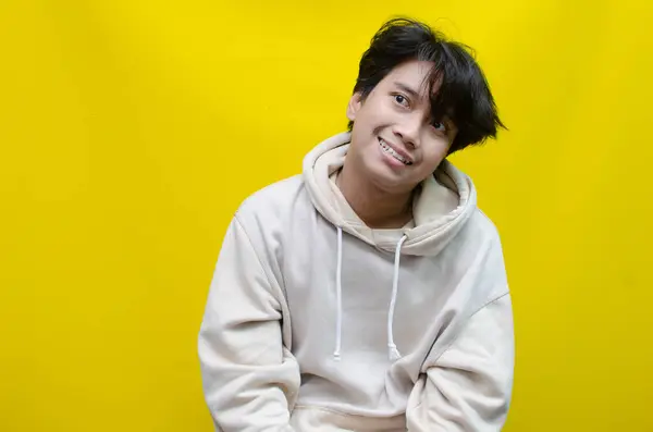 Sarı arka planda gülümseyen Asyalı genç adamın portresi 