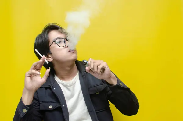 Genç Asyalı adam sigara ve sigara arasında seçim yapıyor. 