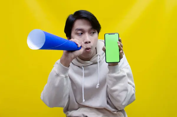 Elinde bej kapüşonlu, elinde yeşil telefon ekranı olan megafonla kendinden geçmiş Asyalı bir adam. Elinde kağıt üzerinde megafon tutan bir adam duyuru yapıyor ve sarı arka planda terfi ettiriyor.