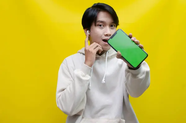 Genç Asyalı adam akıllı telefonu ve kulaklığını kullanıyor. 