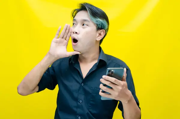 Sarı arka planda akıllı telefonu olan öfkeli Asyalı adam. 