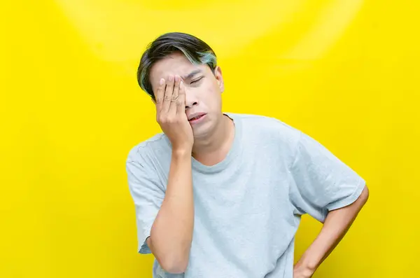 Sarı arka planda ağlayan genç Asyalı adam 