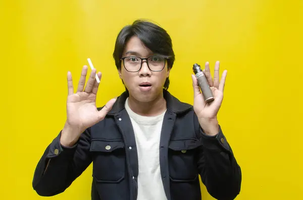 Genç Asyalı adam sigara ve sigara arasında seçim yapıyor. 