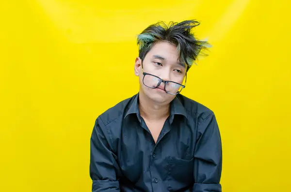 Hüsrana uğramış genç Asyalı adam sarı arka planda 