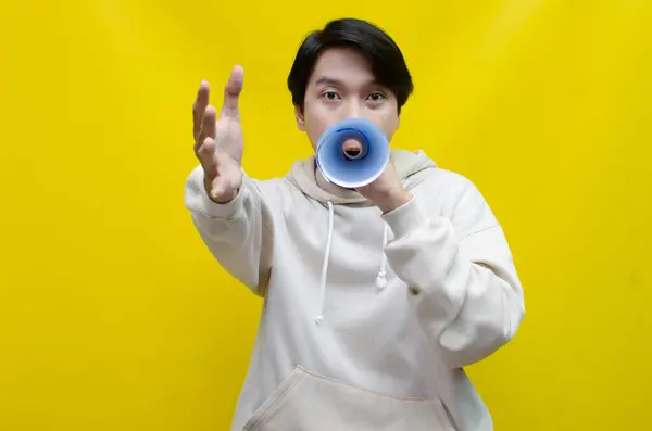 Kağıttan yapılmış megafonu olan heyecanlı Asyalı genç adam. 