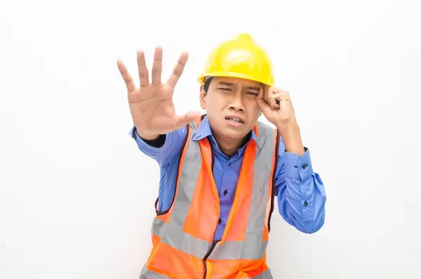 Sarı güvenlik kaskı ve yelek giyen sorunlu Asyalı inşaat işçisi 