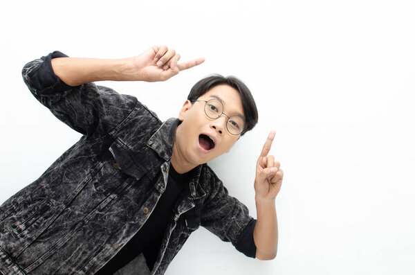 Young Asian man pointing up at studio background