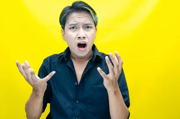 Sarı arka planda bağıran kızgın Asyalı adam 