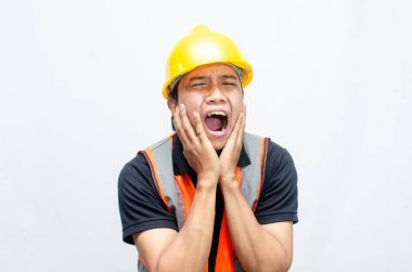 Asyalı Erkek İnşaat İşçisi 'nin Orange Vest ve Sarı Kasklı Kızgın, Kızgın, Üzgün, Kızgın İfadesiyle Aşırı Çalışmış Konsepti. 