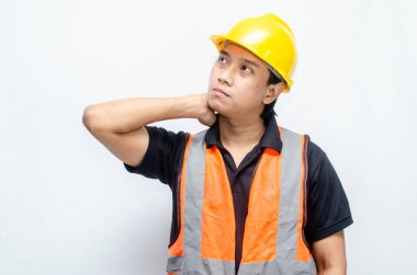 Sarı Miğferli ve Turuncu Yelekli Genç Asyalı İnşaatçı Düşünceli Hareket Ediyor. Derin düşüncelere dalmış, bir fikir arıyormuş. İfadesi düşüncelere dalmış. 