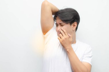 Beyaz tişörtlü genç Asyalı adam beyaz arka planda izole edilmiş Kötü Kokulu Koltuk Altını Kokuyor. Asyalı Adam Utanıyor çünkü Kol çukuru kötü Koku yayıyor 