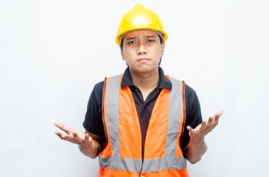 Sarı Miğferli ve Turuncu Yelekli Genç Asyalı İnşaatçı Düşünceli Hareket Ediyor. Derin düşüncelere dalmış, bir fikir arıyormuş. İfadesi düşüncelere dalmış. 