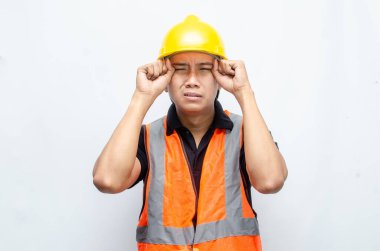 Asyalı Erkek İnşaat İşçisi Hardhat ve Turuncu Yelek Üzgün görünüyor. Aşırı çalışma kavramını vurguladım. İşçi Sigortası Kavramı.