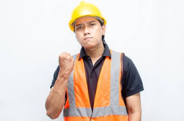 Asyalı inşaat işçisi, sarı sapkalı ve turuncu yelekli ve kaslı. Gücünü ve gücünü göstermek için. Güçlü İşçi Konsepti.