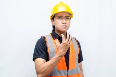 Asyalı inşaat işçisi, sarı sapkalı ve turuncu yelekli ve kaslı. Gücünü ve gücünü göstermek için. Güçlü İşçi Konsepti.