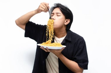 Genç Asyalı Adam Çıplak Elle Kızarmış Erişteyi Ağzına Çiğniyor. Çekici Asyalı adam Eriştelerin ne kadar lezzetli olduğunu gösteriyor..