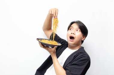 Siyah tişörtlü genç Asyalı adam ve Beyaz tişörtlü... Beyaz arka planda izole edilmiş kızarmış eriştenin tadını çıkaran ve yutan... 