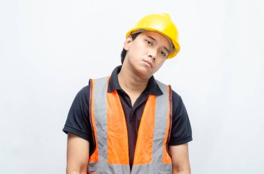 Sarı Miğferli ve Turuncu Yelekli Genç Asyalı İnşaatçı Düşünceli Hareket Ediyor. Derin düşüncelere dalmış, bir fikir arıyormuş. İfadesi düşüncelere dalmış. 