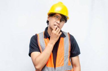 Sarı Miğferli ve Turuncu Yelekli Genç Asyalı İnşaatçı Düşünceli Hareket Ediyor. Derin düşüncelere dalmış, bir fikir arıyormuş. İfadesi düşüncelere dalmış. 