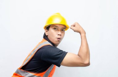 Asyalı inşaat işçisi, sarı sapkalı ve turuncu yelekli ve kaslı. Gücünü ve gücünü göstermek için. Güçlü İşçi Konsepti.