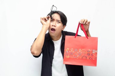 Kırmızı Batik desenli alışveriş çantası tutan çekici ve şık Asyalı genç adam.