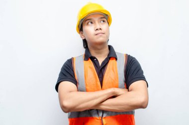 Sarı Miğferli ve Turuncu Yelekli Genç Asyalı İnşaatçı Düşünceli Hareket Ediyor. Derin düşüncelere dalmış, bir fikir arıyormuş. İfadesi düşüncelere dalmış. 