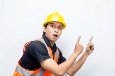 Siyah gömlekli ve sarı kasklı Asyalı mutlu inşaat işçisi reklamları gösteriyor.