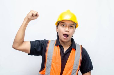 Asyalı inşaat işçisi, sarı sapkalı ve turuncu yelekli ve kaslı. Gücünü ve gücünü göstermek için. Güçlü İşçi Konsepti.