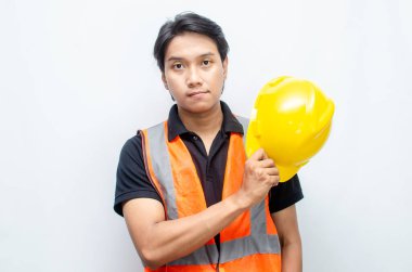 Kendine güvenen genç bir mühendisin portresi veya güvenlik sarı kaskı ve turuncu yelek giyen bir inşaat işçisi.