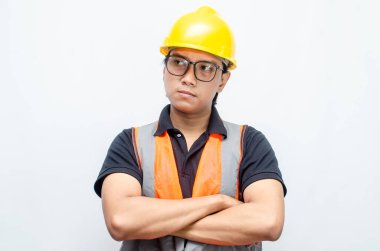 Sarı Miğferli ve Turuncu Yelekli Genç Asyalı İnşaatçı Düşünceli Hareket Ediyor. Derin düşüncelere dalmış, bir fikir arıyormuş. İfadesi düşüncelere dalmış. 